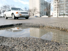 Vehicles pass a large pothole in the northbound lane of Henderson Highway at Stuart Avenue. (Jason Halstead, Winnipeg Sun files)