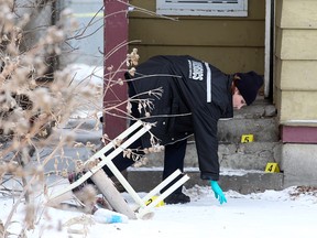 A Winnipeg Police forensics officer investigates behind a house at 691 Selkirk Ave. on Saturday, Dec. 31, 2011, following an early morning shooting that claimed the life of a man and wounded a woman. (Brian Donogh, Winnipeg Sun)