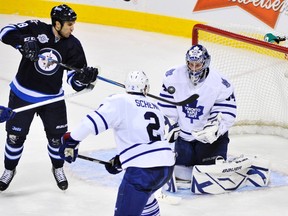 Winnipeg Jets' Patrice Cormier (L) deflects the puck in front of Toronto Maple Leafs goaltender James Reimer during the second period of their NHL hockey game in Winnipeg December 31, 2011. REUTERS/Fred Greenslade