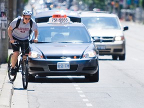 A cyclist detours on the sidewalk while a taxi is stopped along the bike lane. (Ernest Doroszuk/Toronto Sun files)