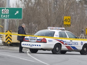 An SIU investigator takes down some notes on the back of a police cruiser near the scene of the shooting. (JACK BOLAND/Toronto Sun/QMI Agency)