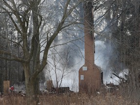 Investigators sift through the rubble after a fire gutted an abandoned house outside of Toronto. All that still stands is the chimney. The building is on land that has been expropriated by the federal government and has an interesting past: A dungeon was discovered in the house just last year. Stan Behal/QMI AGENCY