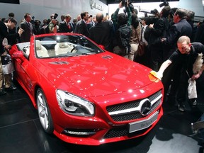 A worker removes fingerprints from the 2013 Mercedes Benz SL on the first press preview day at the North American International Auto Show in Detroit, Michigan on the first press preview day in Detroit, Michigan, Jan. 9, 2012.  REUTERS/Rebecca Cook