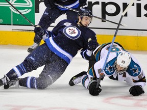 Jets centre Alex Burmistrov collides with Ryan Clowe of the Sharks during San Jose’s 2-0 win Thursday night at MTS Centre.