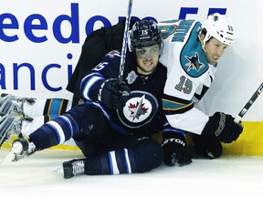 Glass, seen crashing into the boards with San Jose’s Joe Thornton on Thursday, said the Jets have to keep believing in themselves despite losing four of five to begin the calendar year. (MARIANNE HELM/AFP-Getty Images)