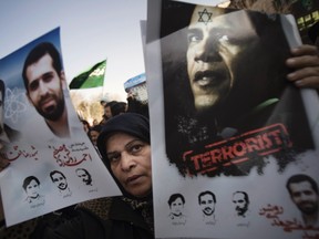 A worshipper holds an anti-U.S. President Barack Obama poster and portraits of killed Iranian nuclear scientists during the funeral for nuclear scientist Mostafa Ahmadi-Roshan, who was killed in a bomb blast in Tehran on January 11, after Friday prayers January 13, 2012. (REUTERS/Morteza Nikoubazl)