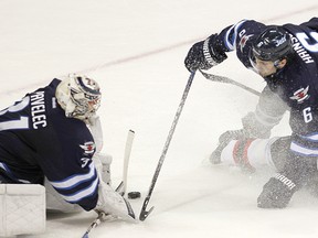 Winnipeg Jets goalie Ondrej Pavelec (left) blocks the puck as defenceman Ron Hainsey (centre) and New Jersey Devils' Patrik Elias hit the ice during their NHL tilt at the MTS Centre on Saturday, Jan. 14, 2012. (BRIAN DONOGH/WINNIPEG SUN)