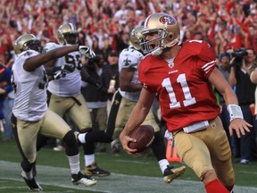 San Francisco 49ers quarterback Alex Smith reacts as he scores a fourth quarter touchdown as New Orleans Saints defenders (L) follow during their NFL NFC Divisional playoff football game in San Francisco, California, January 14, 2012.   REUTERS/Robert Galbraith