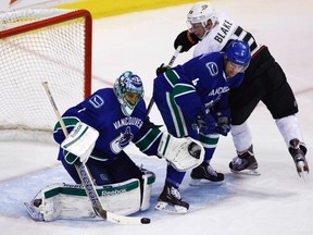 Vancouver Canucks goaltender Roberto Luongo makes a save while teammate Keith Ballard checks Anaheim Ducks Jason Blake during the second period of their NHL hockey game in Vancouver, British Columbia January 15, 2012.   REUTERS/Ben Nelms