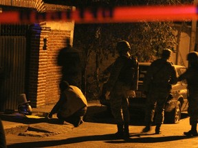 Police stand near a motorcycle helmet containing a human head and topped with a foam hat with the writing "Happy 2012" placed outside a house in a residential area in Morelos January 16, 2012. According to the Foreign Affairs Department, over 110 Canadians have died in Mexico since 2006. REUTERS/Margarito Perez Retana