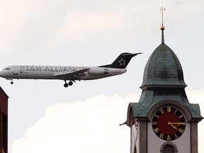 A Fokker 100 of Star Alliance airline is seen behind a church tower during its approach for a landing at Zurich Airport in the town of Kloten April 12, 2011.  REUTERS/Arnd Wiegmann