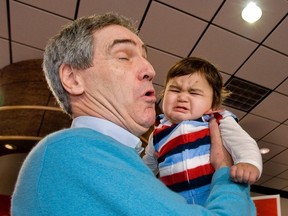 Michael Ignatieff holds a crying baby in Toronto, April 8, 2011. (Alex Urosevic/QMI Agency, file)