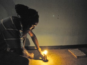 At a vigil in Kingston, Jamaica, on Wednesday, Omar Edwards, a resident who stormed the house of Alphanso and Stephanie Warren to discover the remains of Baby Joshua places a candle and a bible at the spot where the decomposed remains were found. (Special to the Sun)