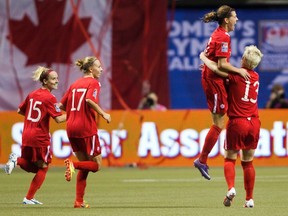 Christine Sinclair jumps into Sophie Schmidt's arms after their team defeated Mexico to qualify for the 2012 Olympics after their semi-final CONCACAF Women's Olympic qualifying soccer match in Vancouver, British Columbia January 27, 2012.    (REUTERS/Ben Nelms)