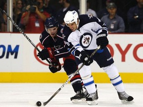 Spencer Machacek (right) fights for the puck with Columbus Blue Jackets’ Oliver Gabriel during a pre-season game last September. The Jets called up the gritty winger, who coach Claude Noel says ‘plays the game like he wants to win.’ (MATT SULLIVAN/Reuters files)