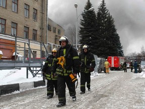 Firefighters work on the territory of a nuclear research institute, with heavy smoke seen in the background, in Moscow Feb. 5, 2012.  A fire broke out on Sunday at a Moscow nuclear research centre, according to local media.   REUTERS/Mikhail Voskresensky