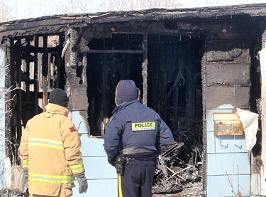 A fire investigator (left) and a member of the RCMP investigate a burned out trailer in Selkirk, Man., on Saturday, Feb. 11, 2012 following an early morning fire that claimed four lives. (BRIAN DONOGH, Winnipeg Sun)