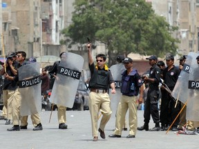 A Pakistani police officer fires in the air to disperse residents of southern neighbourhood Lyari during a protest against the government and police operation in troubled Lyari area in Karachi on April 30, 2012.  At least 12 people including police officials were killed and several injured in three days in Lyari operation by Pakistani police swoop in the neighbourhood infested with criminal gangs, local media reported.  AFP PHOTO/Rizwan TABASSUM