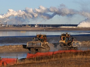 Workers use heavy machinery in the tailings pond at the Syncrude oil sands extraction facility near the town of Fort McMurray, Alberta on October 25, 2009.  (AFP PHOTO/Mark RALSTON)