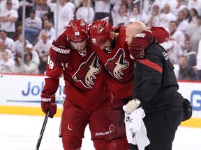 Michal Rozsival, of the Phoenix Coyotes, is helped off the ice by Mikkel Boedker and a Coyotes trainer after a hit by Dustin Brown. (GETTY)