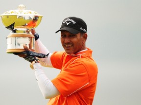 India's Jeev Milkha Singh poses for photographers with the winners trophy after winning the Scottish Open golf tournament after an extra hole play off against Italy's Francesco Molinari at Castle Stuart golf course near Inverness, Scotland July 15, 2012. (REUTERS/David Moir)