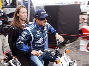 Canada's Alex Tagliani of Team Barracuda-BHA rides his scooter with team PR person Emily Jones following the Indy Car Series qualifying session at the Edmonton Indy. REUTERS/Dan Riedlhuber