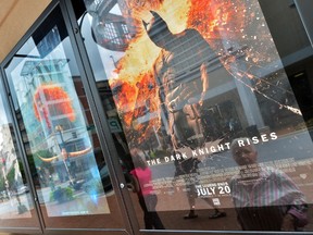 People walk past a poster of the new Batman movie  "The Dark Knight Rises" outside a theater in Silver Spring, Maryland, on July 20, 2012. (AFP PHOTO/Jewel Samad)