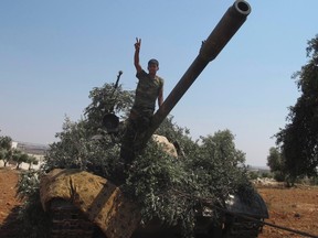 A member of the Free Syrian Army flashes the victory sign on a captured tank after taking control of a checkpoint from government forces in Anadan, north Aleppo, July 31, 2012. REUTERS/Obeida Al Naimi