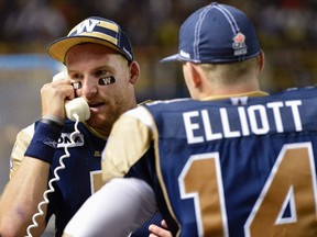 Bombers QB Alex Brink (left) talks to coaches on the telephone as Joey Elliott, the Bombers backup pivot, looks on. (Fred Greenslade/REUTERS)
