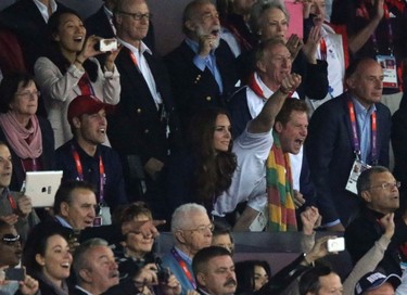 Britain's Prince Harry gestures next to Catherine, Duchess of Cambridge and Prince William (red cap) as they watch the men's 100m final at the Olympic Stadium during the London 2012 Olympic Games August 5, 2012. (REUTERS/Luke MacGregor)