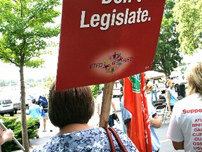 Marchers carry  signs during a Labour Day 2012 rally. - CHRISTOPHER SMITH, The Expositor/QMI