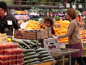 Whole Foods grocery store worker Adam Pacheco (L) stacks vegetables while customers shop in the produce section at the Whole Foods grocery story in Ann Arbor, Michigan, March 8, 2012. (REUTERS/Rebecca Cook )