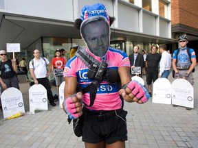 Cyclist Dennis VanHoekelen wears a Michael Bryant mask as he steers his way through protesters Wednesday, Sept. 5, 2012. (Stan Behal/Toronto Sun)