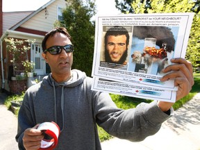 Ron Banerjee from the Canadian Hindu Advocacy holds up posters last May in the Scarborough neighbourhood where Omar Khadr's grandfather lives. (Craig Robertson/QMI Agency)