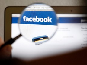 In this photo illustration, a Facebook logo on a computer screen is seen through a magnifying glass held by a woman in Bern, May 19, 2012. (REUTERS/Thomas Hodel)