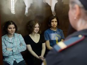 Members of the all-girl punk band "Pussy Riot" Nadezhda Tolokonnikova (R), Maria Alyokhina (R) and Yekaterina Samutsevich (C) sit in a glass-walled cage during a court hearing in Moscow on Agust 17, 2012. (AFP/NATALIA KOLESNIKOVA)