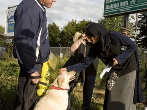 Dr. Tabasum Hussain, right, a member of the mosque pets the head of Duncan Jaffray's golden lab Chelsea. Jaffray was just walking by and became unwittingly part of the protest.(Jack Boland/Toronto Sun)