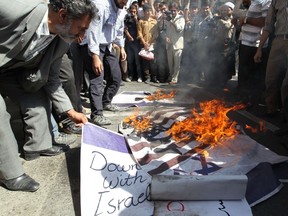 Iranian men burn the US and Israeli flags during a demonstration against the publication by a French satirical weekly of a cartoon of a naked Prophet Mohammed, on September 20, 2012 outside France's embassy in Tehran. (AFP PHOTO/ATTA KENARE)