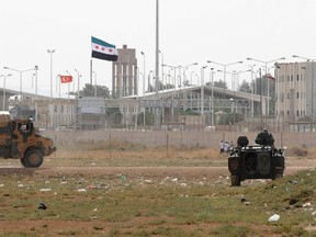 Turkish troops take their position at the Akcakale border gate in southern Sanliurfa province October 7, 2012, as a Syrian Independence flag waves at Syria's Tel Abyad border crossing in the background. REUTERS/Stringer