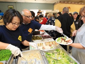 (left to right) Volunteers May Feng and Suresh Agarwal help serve up food during the Millbourne Maytag Laundromat's, 109 Millbourne Road East, annual free Thanksgiving Luncheon, Monday Oct. 8, 2012.  DAVID BLOOM EDMONTON SUN  QMI AGENCY