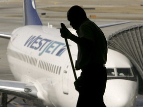 A janitor cleans a window ledge near a WestJet plane at the Calgary International Airport in this April 16, 2010 file photo. (QMI Agency files)