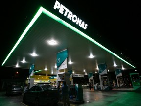 Motorists pump petrol at a Petronas station in Putrajaya in this December 8, 2009 file photograph. The Canadian government blocked the C$5.17 billion (3.2 billion pounds) acquisition of Progress Energy Resources Corp by Malaysian state oil company Petronas, raising questions about other, bigger bids and about Canada's willingness to let foreign investors in. (REUTERS/Bazuki Muhammad/Files)