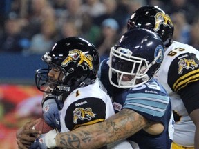 Tiger-Cats quarterback Henry Burris (left) is tackled by Argonauts’ Ricky Foley last night at the Rogers Centre. (REUTERS)