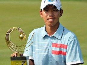 Guan Tianlang of China squats as he holds his winner's trophy during the final day of the Asia-Pacific Amateur Championship at Amata Spring Country Club in Chonburi November 4, 2012. Guan is poised to become the youngest golfer to play at the U.S. Masters after the Chinese 14-year-old won the Asia-Pacific Amateur Championship in Thailand on Sunday. (REUTERS/Paul Lakatos/OneAsia/Handout)