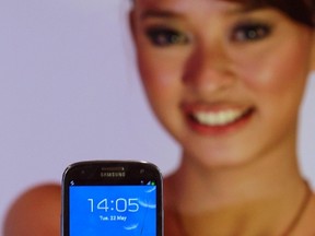 A woman presents the Samsung Galaxy S3 smartphone during its product launch in Jakarta in this May 22, 2012 file photo.  REUTERS/Beawiharta/Files