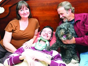 Charlie Smith, centre, was bedridden and suffering from severe symptoms of EDS  before a surgery in the United States put him back on his feet. With Charlie is mother Christine and father Duane Smith and dog Harley.
(RECORDER AND TIMES FILE PHOTO)