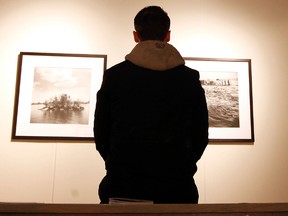 A man is photographed looking at the photography of Pedro Itzin inside the City Hall Art Gallery at Ottawa City Hall on Monday. (Darren Brown/Ottawa Sun)