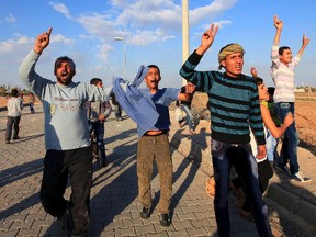 Syrian men from the town of Ras al-Ain shout slogans after crossing border fences in the border town of Ceylanpinar, Sanliurfa province November 14, 2012. A Syrian warplane bombed the town of Ras al-Ain near the Turkish border for a third day on Wednesday as forces loyal to President Bashar al-Assad pressed an air assault to dislodge rebels. REUTERS/Stringer