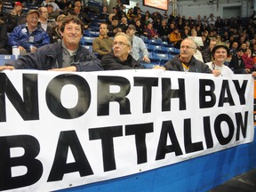 Rick Vezina, left, and Brandon Joyes, right, sporting his Battalion army helmet, display a sign honouring their new team during the Brampton Battalion's 4-2 win over the Sudbury Wolves at Sudbury Arena, Wednesday (Gino Donato/QMI Agency)