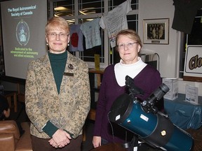 Head librarian Kathryn Foley accepts the donation of a telescope from Katherine Peterson, councillor of the Royal Astronomical Society of Canada, Calgary Centre. It will be available to check out.